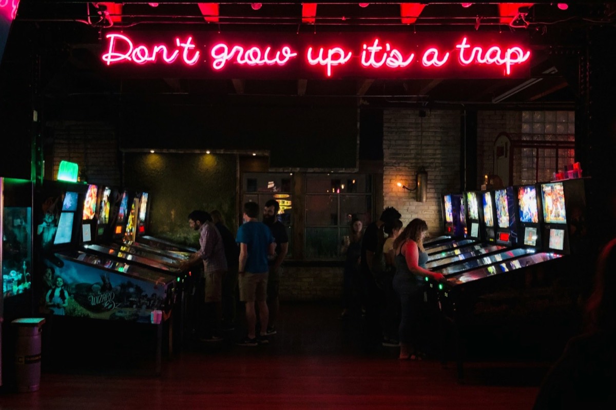 People playing arcade games under a neon sign