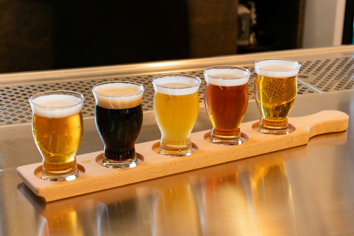 A flight of five beers on a wooden paddle